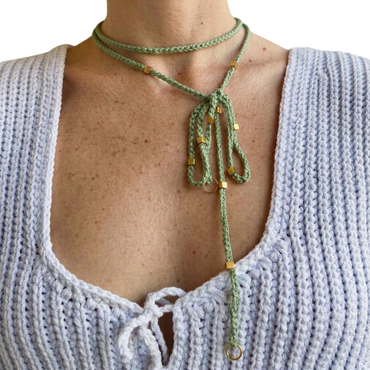 Doppio Senso Dettagli Oro È NA ROBA: collana artigianale in cotone verde salvia con perline dorate, indossata come lariat