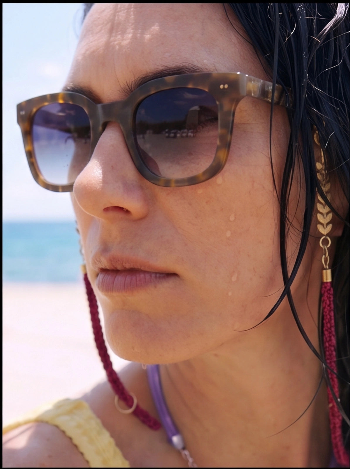 Cordino occhiali Click&Change ORO È NA ROBA con charm dorati a foglia, catena oro e corda bordeaux, indossato in spiaggia